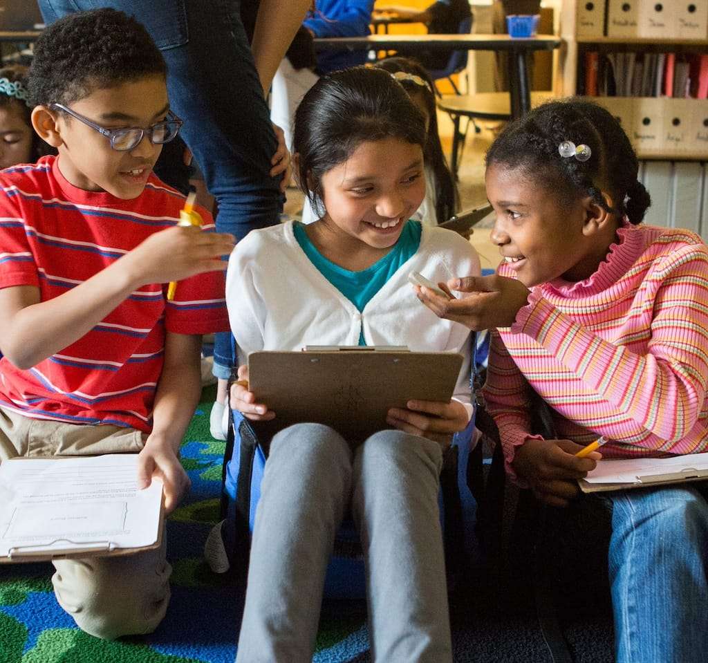 Three third-graders reading books together